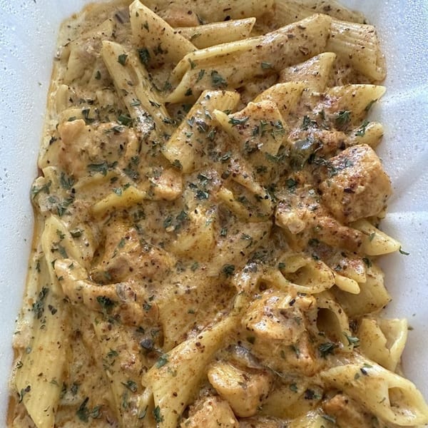Creamy penne pasta with chicken and herbs, a Caribbean-inspired dish from JS International Grill.