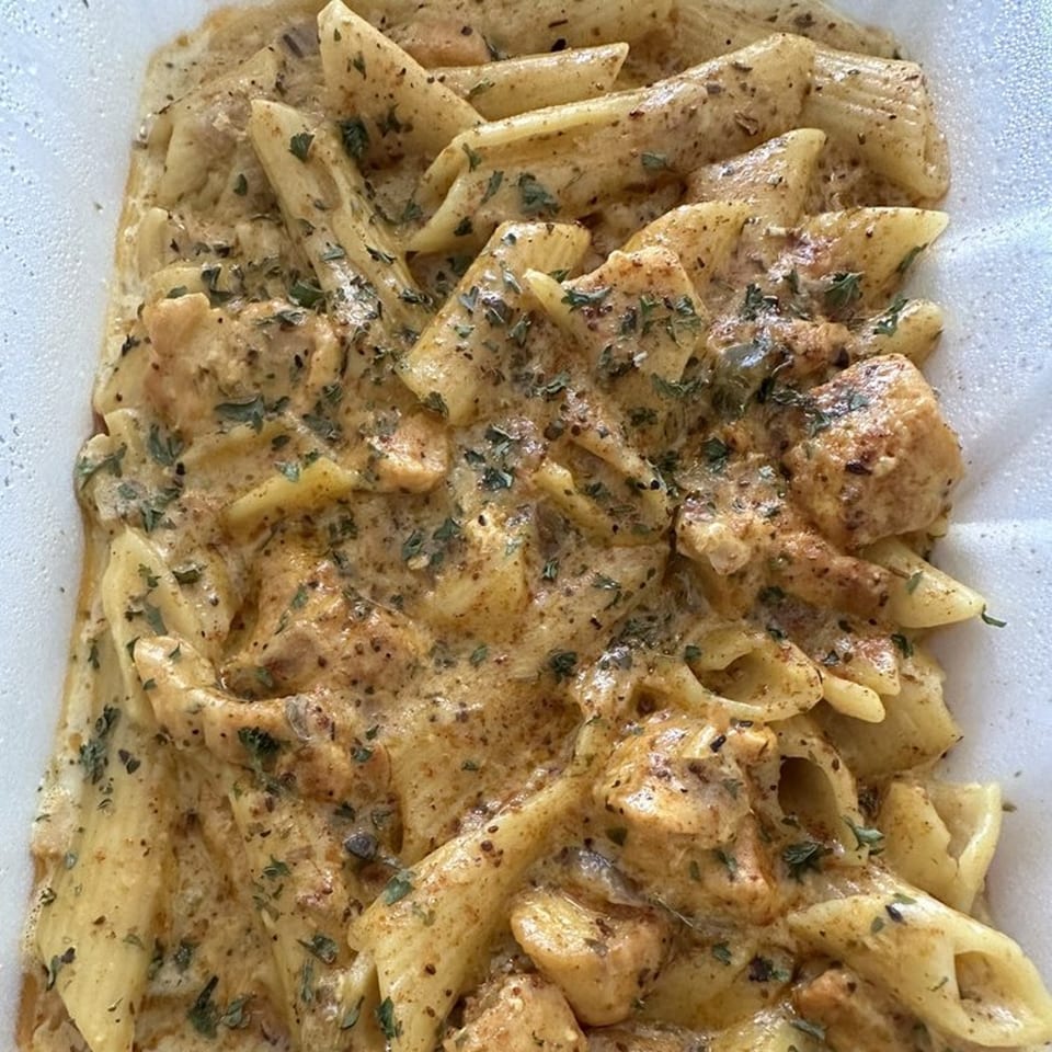Creamy penne pasta with chicken and herbs, a Caribbean-inspired dish from JS International Grill.